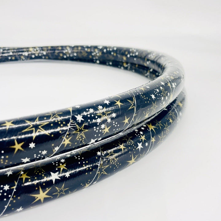 Beginner weighted hula hoop. Collapsed into two coils for travel in gold star duct tape. Black tape with gold stars