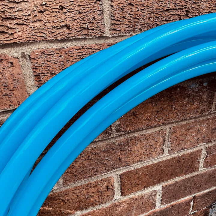 bioluminescent blue gloss hula hoops for hula hooping. Against a brick wall