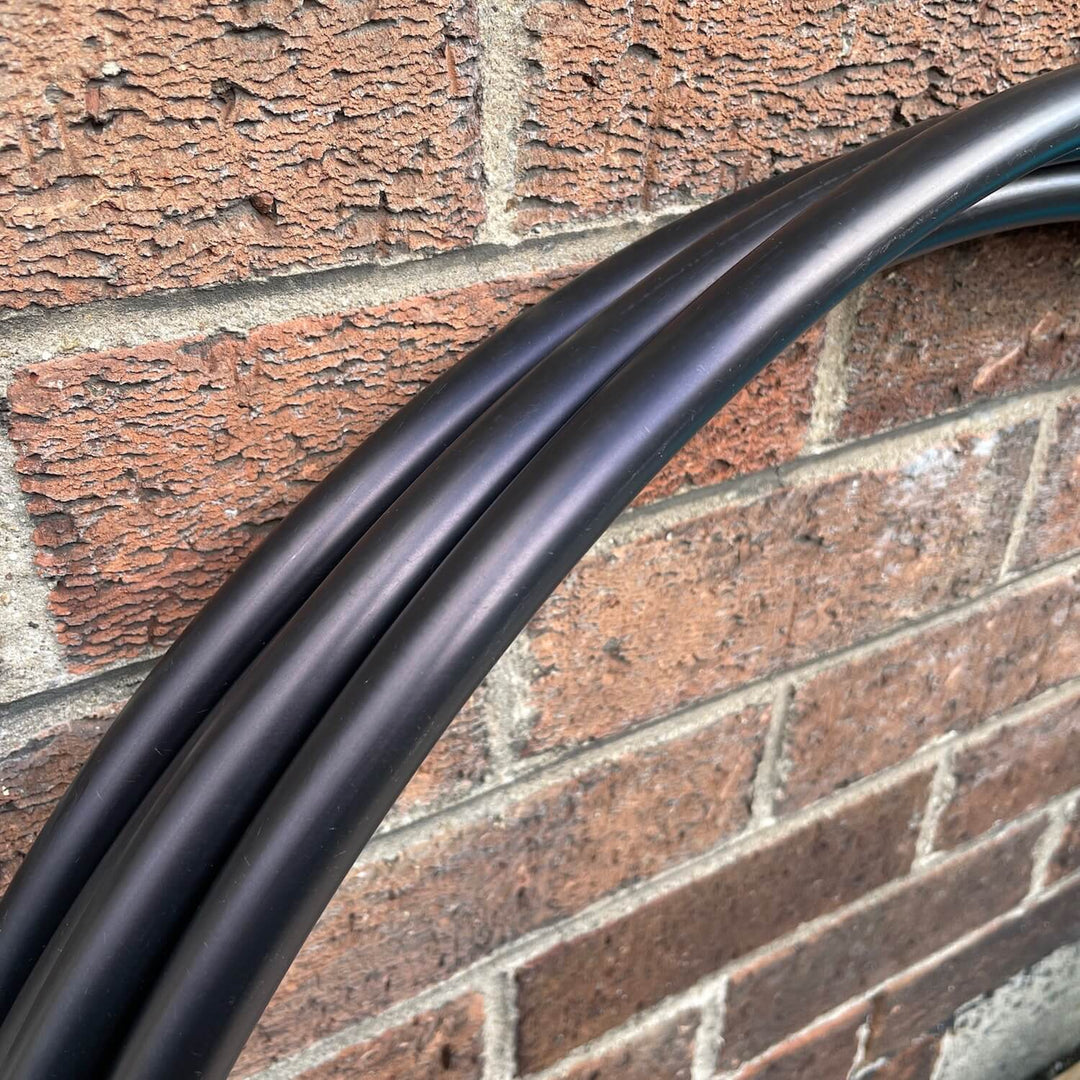 Black Widow black hula hoop for adult hula hooping  resting against a brick wall